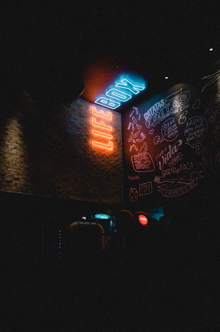 Services Neon 'LIFE BOX' sign glowing in a dimly lit urban environment with graffiti art.