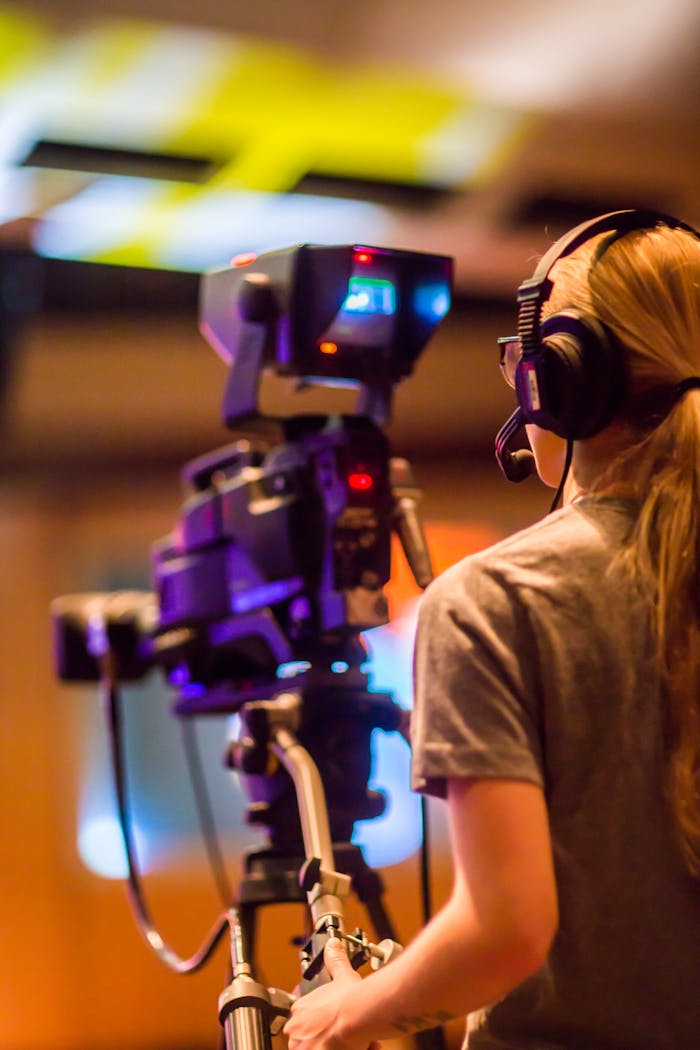 Services A woman operates a professional camera indoors, focusing on media production.